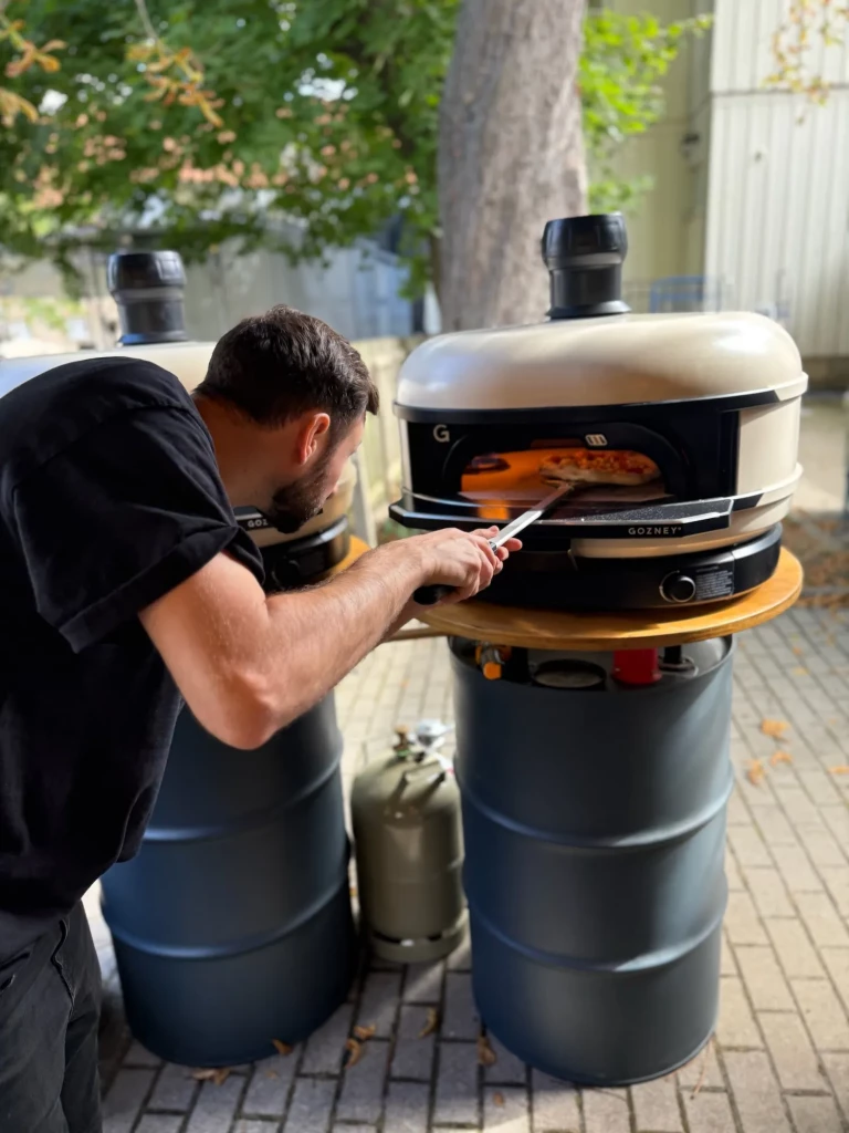 Pizzabäcker schiebt eine Pizza in den Gasofen am Stand in Wennigsen