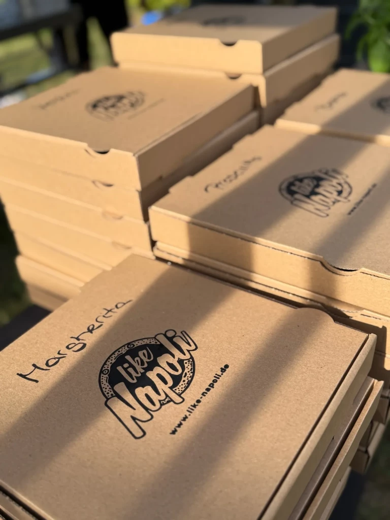 Gestapelte Like-Napoli-Pizzakartons mit handbeschrifteten Sorten in der Spätsommersonne