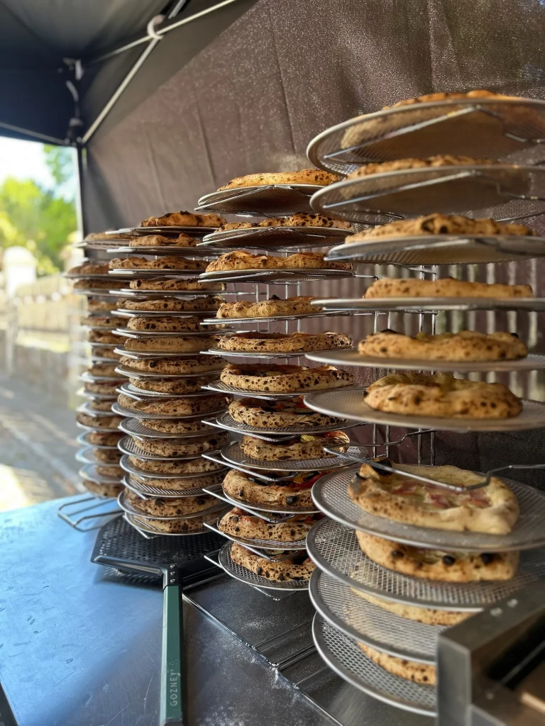 Vorgebackene Pizzen stapeln sich auf Gittern – Vorbereitung auf den Andrang der Weinwanderung